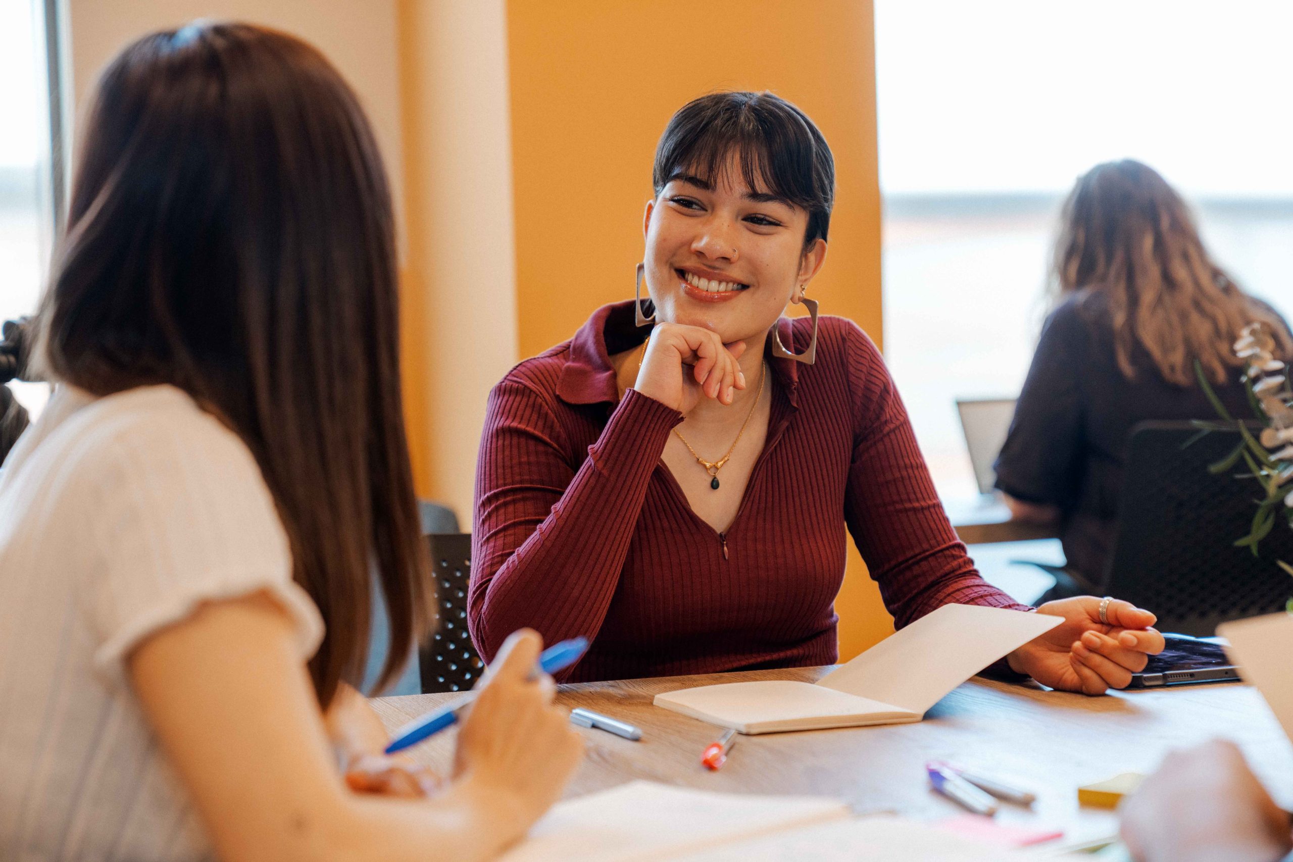 International students smile at each other whilst working
