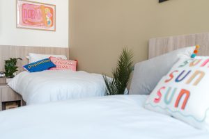 Twin student accommodation room with two beds and brightly coloured pillows