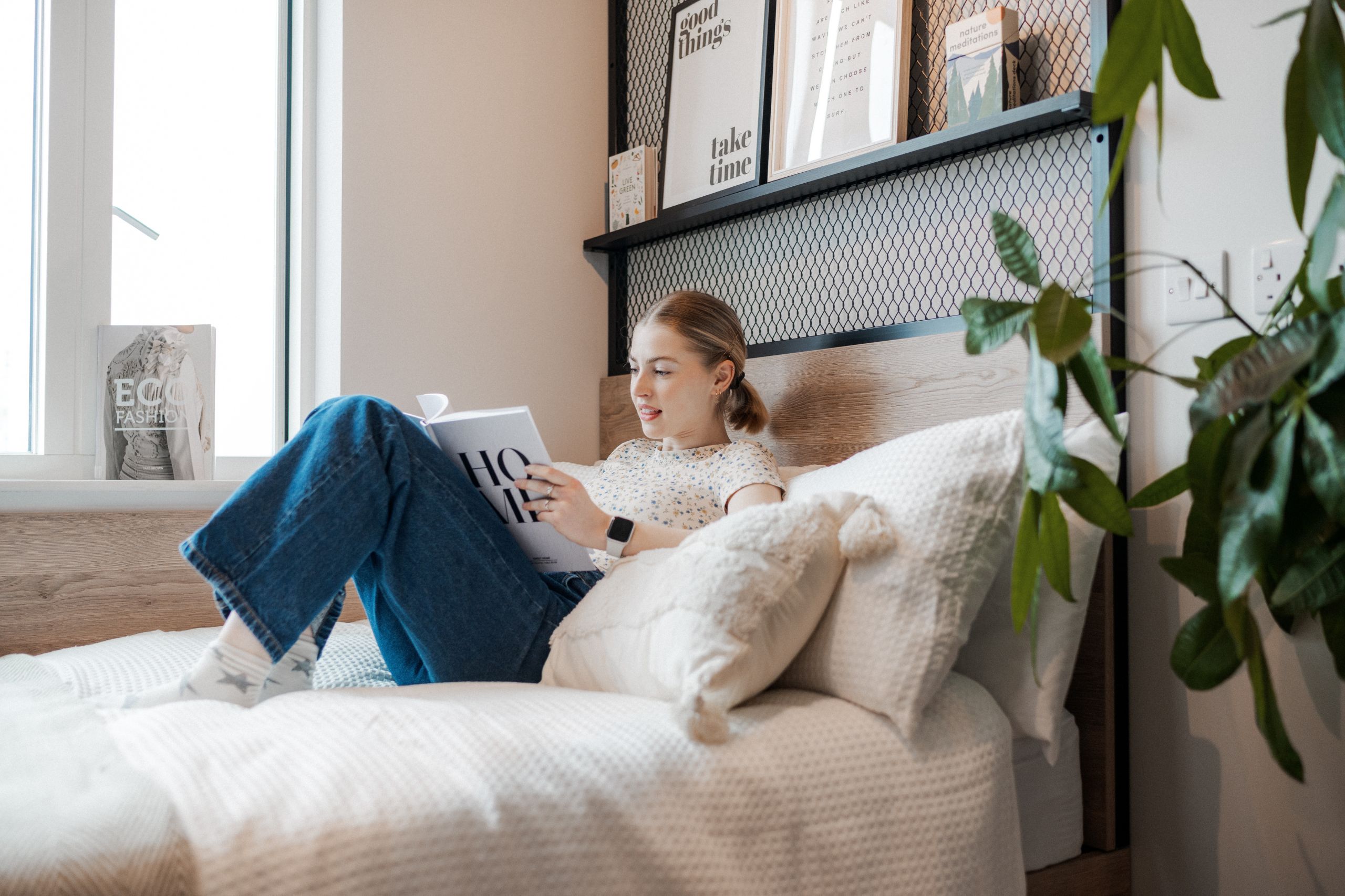 Student sits on white bedding with book