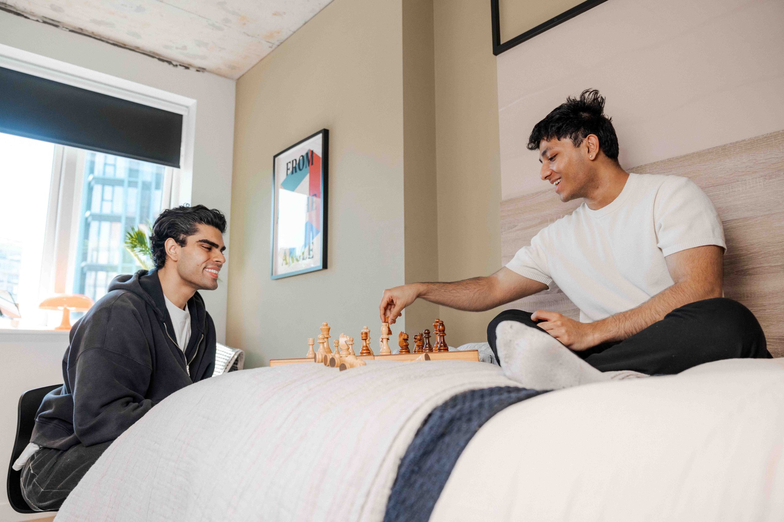 Two students play games on their bed