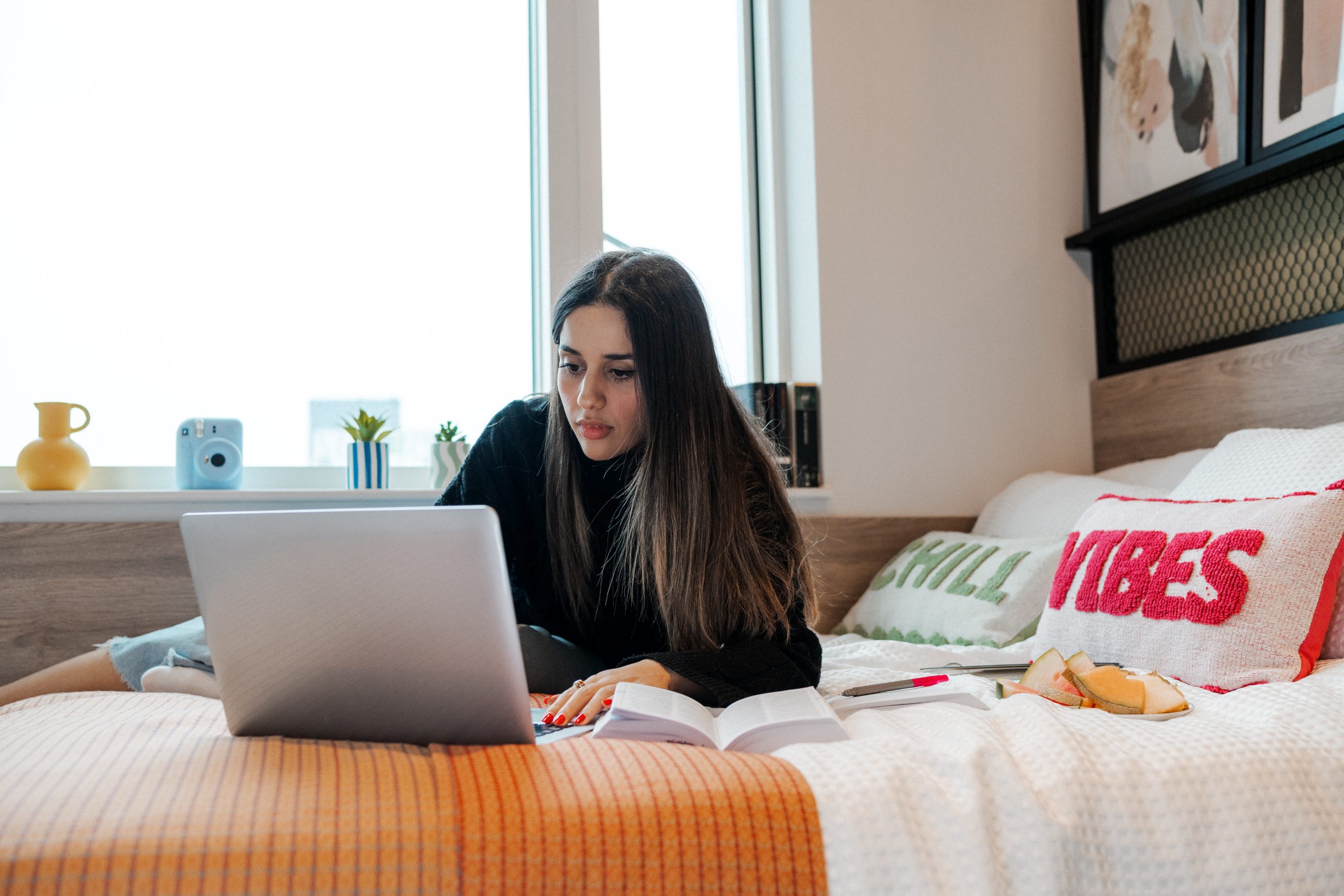 Student laid on her bed on her laptop