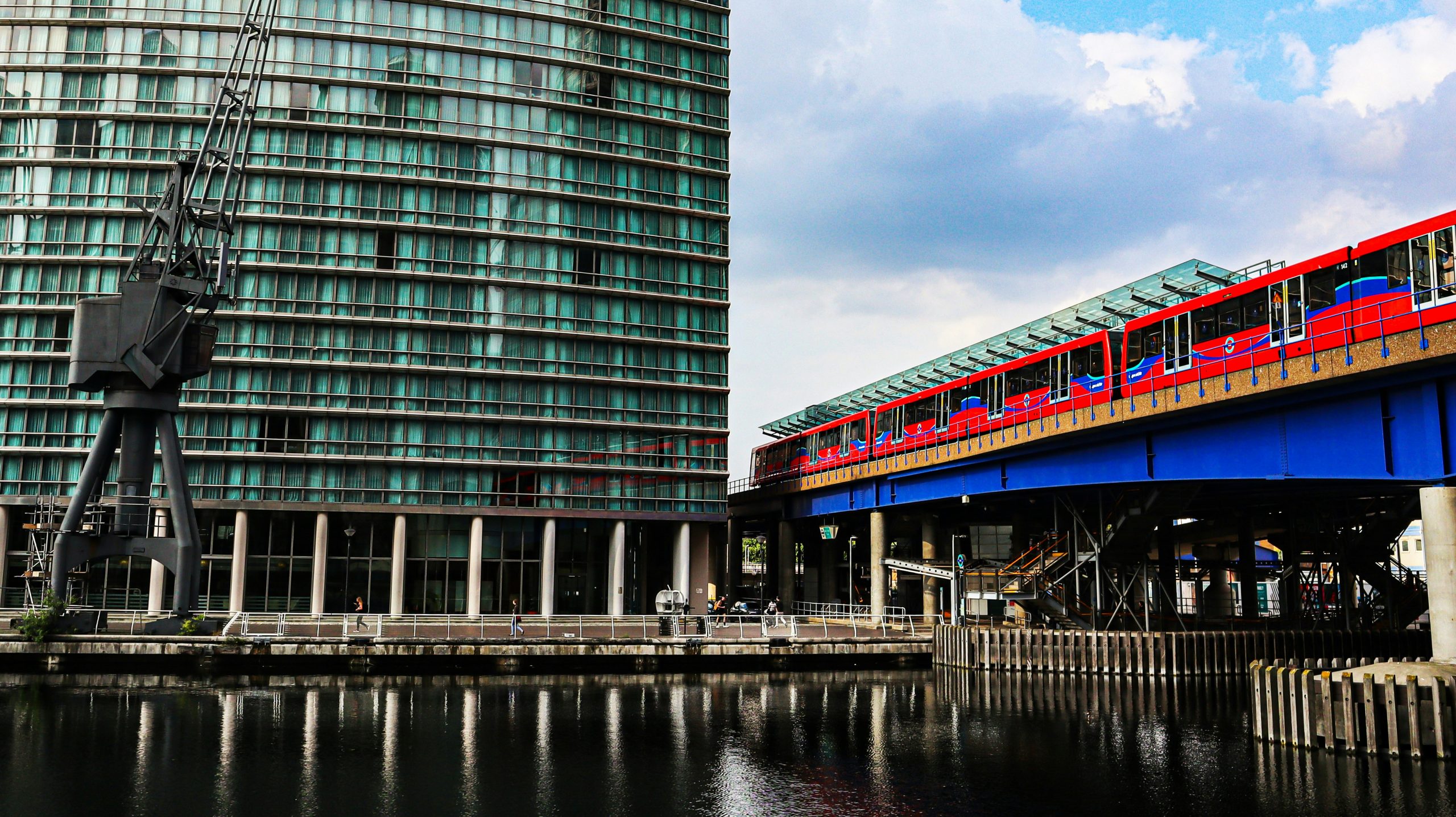 Red DLR train crossing an elevated track beside the water