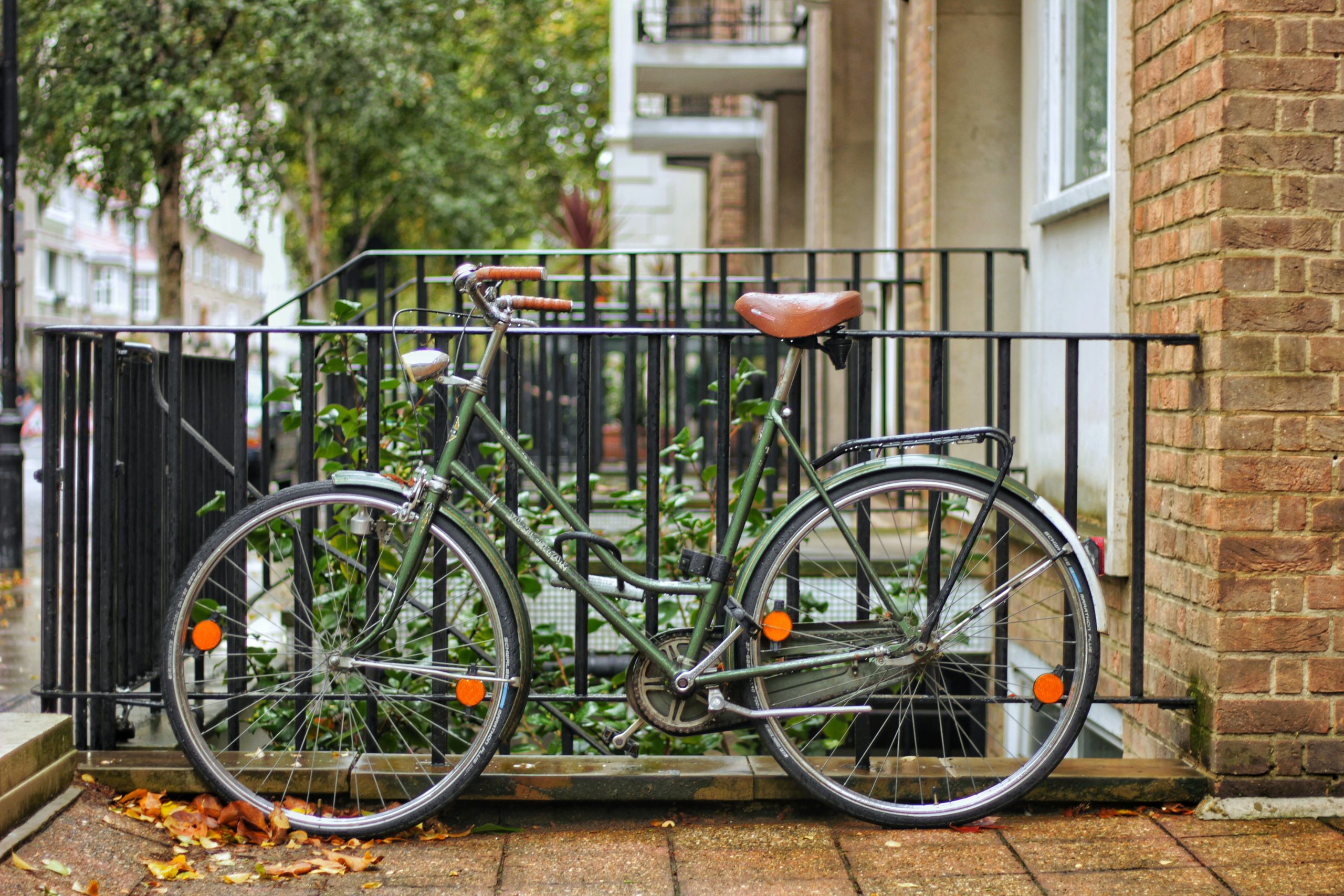 Green bicycle parked beside a railing on a residential street